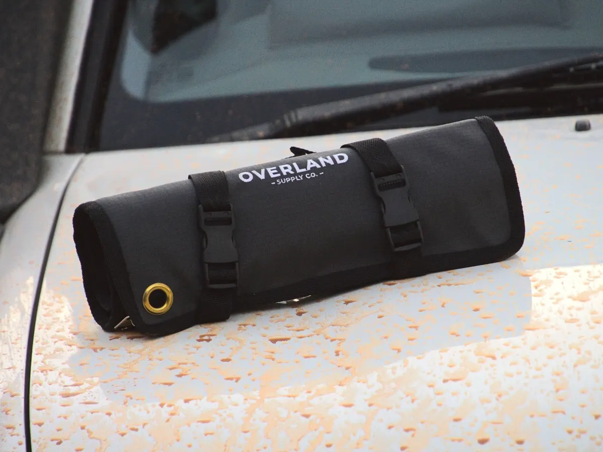 The Tool Roll rolled up on the mud-splattered bonnet of a white Land Cruiser, brass eyelet and buckles in front